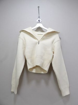 un pull blanc suspendu à un cintre accroché au mur
