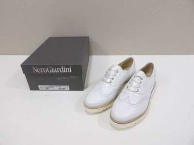 pair of white leather shoes with white laces on a white table
