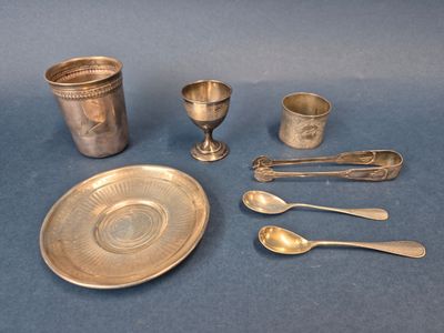 des couverts et des cuillères posés sur une nappe bleue, avec une tasse et une soucoupe