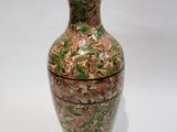 un vase vert et marron posé sur une surface blanche
