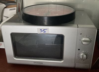 un micro-ondes avec une horloge au-dessus, posé sur un plan de travail
