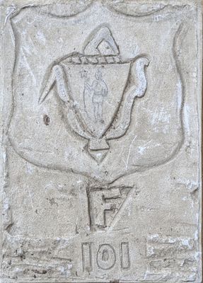 plaque en ciment représentant un trophée, apposée sur la façade d'un bâtiment