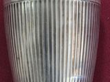 un vase en argent sur lequel est inscrit un nom, posé sur un tissu rouge