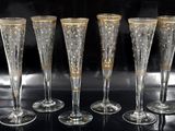 four champagne flutes with gold rims on a black surface