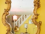 a mirror hanging on a yellow wall in a living room