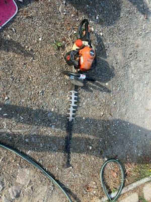 une tronçonneuse posée par terre à côté d'un tuyau d'arrosage
