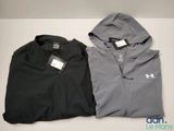 deux vestes Under Armour pour homme posées sur une surface blanche