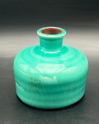a small green vase sitting on a black surface