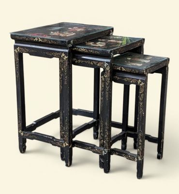 trois tables gigognes noires ornées de motifs floraux sur fond blanc