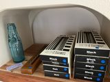 several boxes of black and white ink sitting on a shelf next to a blue bottle