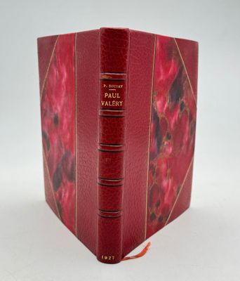 un vieux livre à la couverture rouge posé sur une table blanche