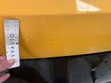 someone is measuring the height of a yellow car with a ruler