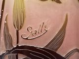 a close up of a vase with flowers and leaves on it