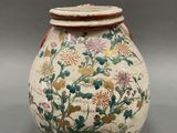 an image of a vase with flowers and leaves painted on it