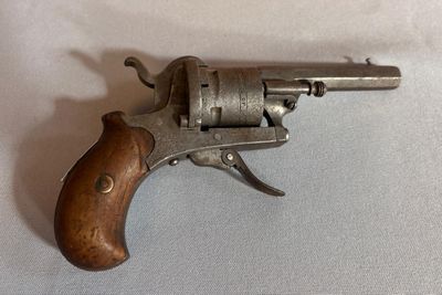 un vieux pistolet avec une poignée en bois sur une surface blanche
