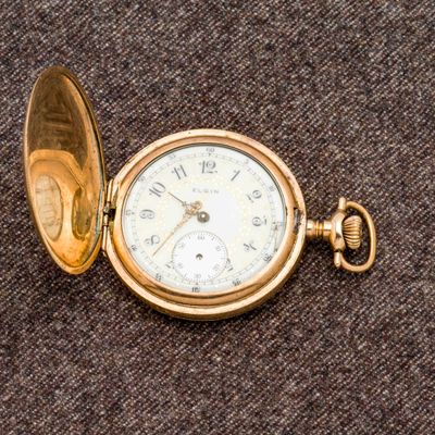 une montre de poche en or posée sur un tissu marron