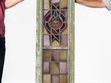 two people standing next to a tall stained glass window in a room