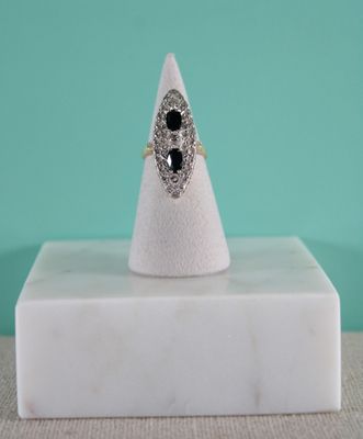 une image représentant une bague ornée d'une pierre noire posée sur un bloc de marbre blanc