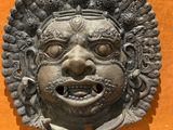 statue of a man ' s face on a wall in a museum