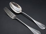 two silver spoons and a fork on a black background