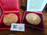 two gold medals in a red case on a table