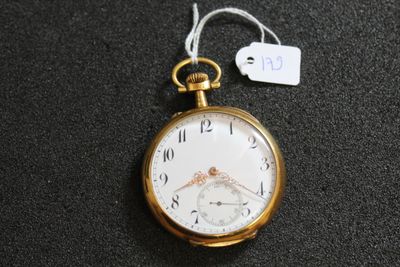 une montre de poche en or posée sur une surface noire, avec une étiquette de prix