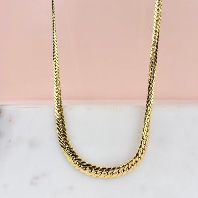 un collier à chaîne en or posé sur un comptoir en marbre