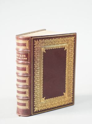 an old book with gold trim and a brown cover sitting on a white surface
