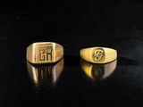 two gold rings with initials on them on a black surface