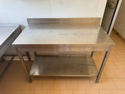 une table en acier inoxydable dans une cuisine au sol carrelé