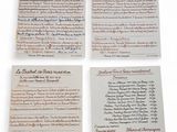 four pieces of paper with writing on them sitting on a table