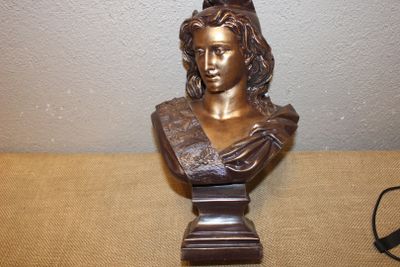 un buste en bronze représentant une femme assise, posé sur une table