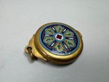 a small gold and blue object on a white surface