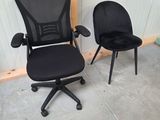 pair of black office chairs with arms and backrests on concrete floor