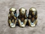 trois singes sages assis sur une table, la main posée sur le menton