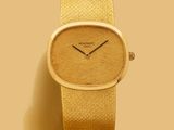 une montre en or posée sur une table, à côté d'autres objets