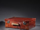 une valise marron munie d'une poignée, posée sur une surface grise