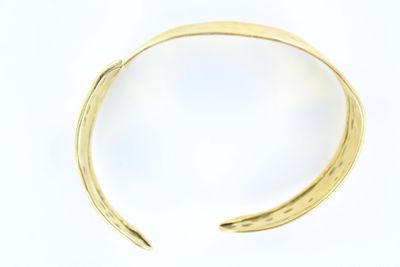 un gros plan sur un bracelet en or au motif incurvé