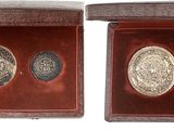 two silver coins in a wooden box on a white background