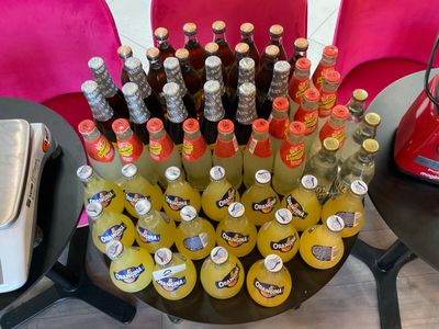 many bottles of soda and orange juice on the table