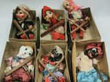 six boxes of dolls are lined up in a row on a white surface