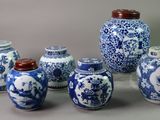 several blue and white vases with lids are lined up on a table