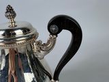 an antique silver tea pot with a black handle on a white background