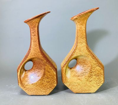une paire de vases jaunes percés de trous, posés sur une table