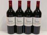 four bottles of red wine are lined up on a table