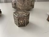 a small silver box sitting on a table next to other silver objects