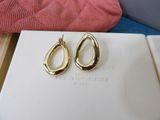 pair of gold tone earrings on a white book with a pink pillow