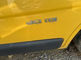 a close up of a yellow car with a cat underneath it