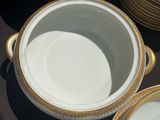 a lot of white and gold plates and bowls on a table