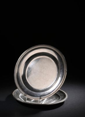 une assiette ancienne en argent posée sur une surface noire avec un fond noir